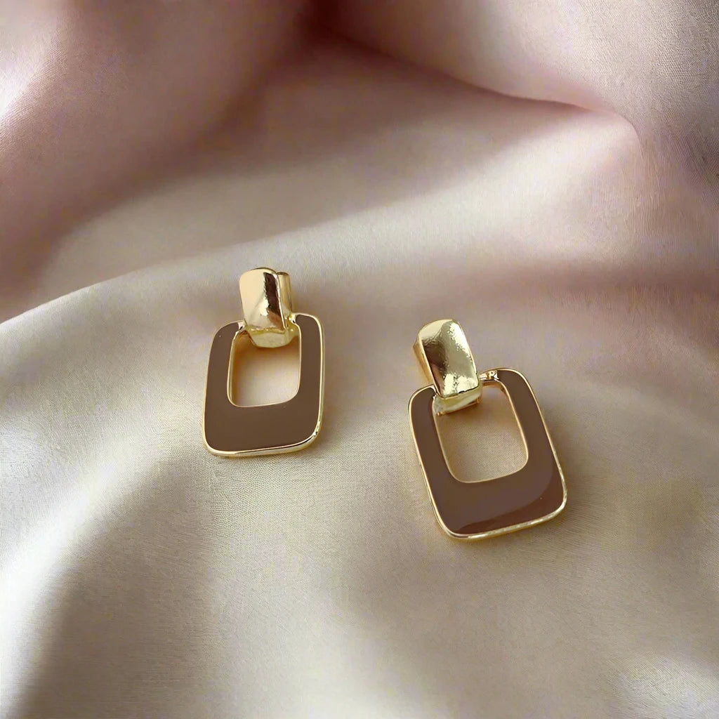 A pair of brown square drop earrings with a gold-tone frame.