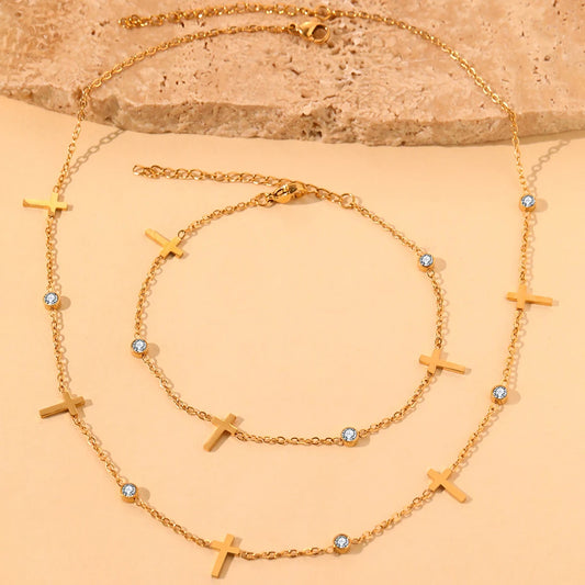 A set of two gold necklaces with multiple small crosses and clear crystals.