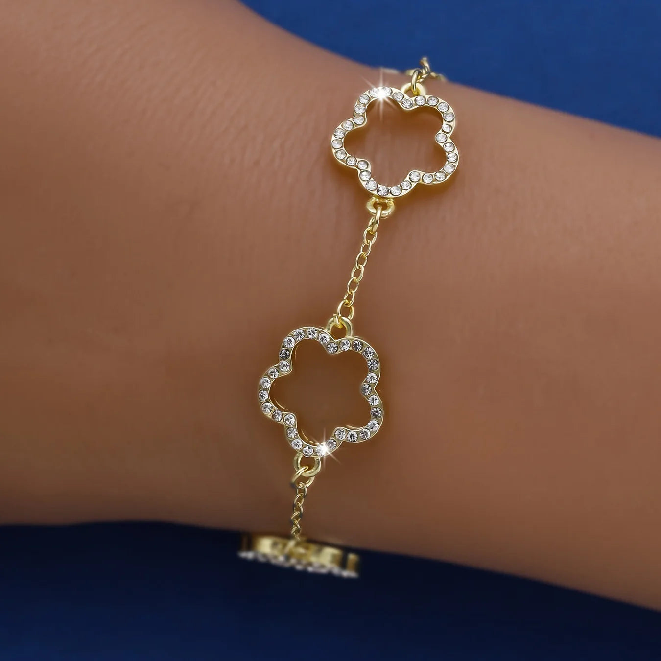 A dainty gold bracelet with flower charms and sparkling crystals.