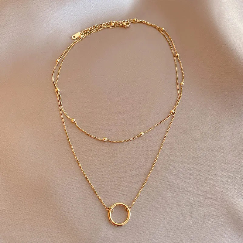 A dainty gold necklace with a delicate circle pendant and small beads.