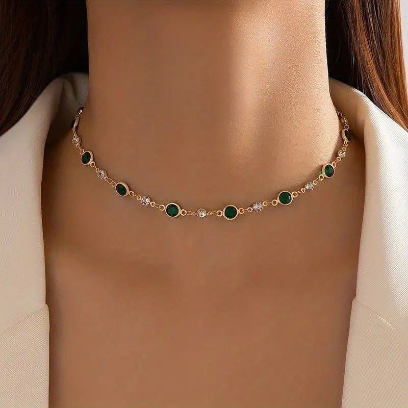 A dainty gold choker with green and clear crystals.