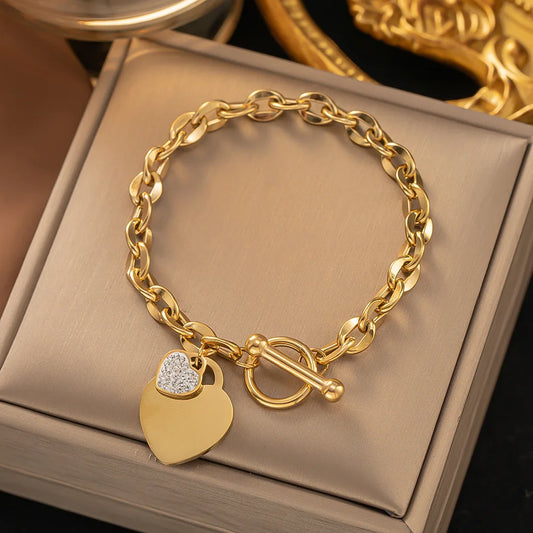 Gold-toned chain bracelet with a dangling heart charm adorned with crystals