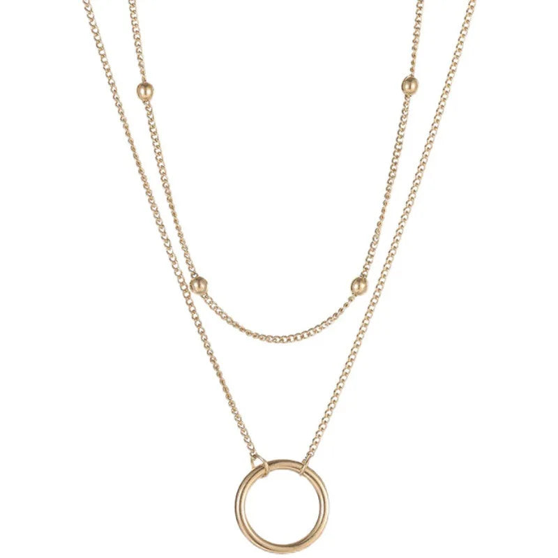 A gold necklace with a circle pendant and two layers of chain.