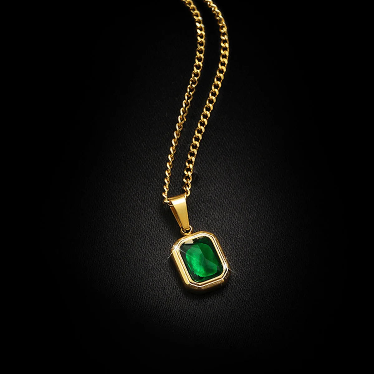 A minimalist gold necklace with a square emerald gemstone.