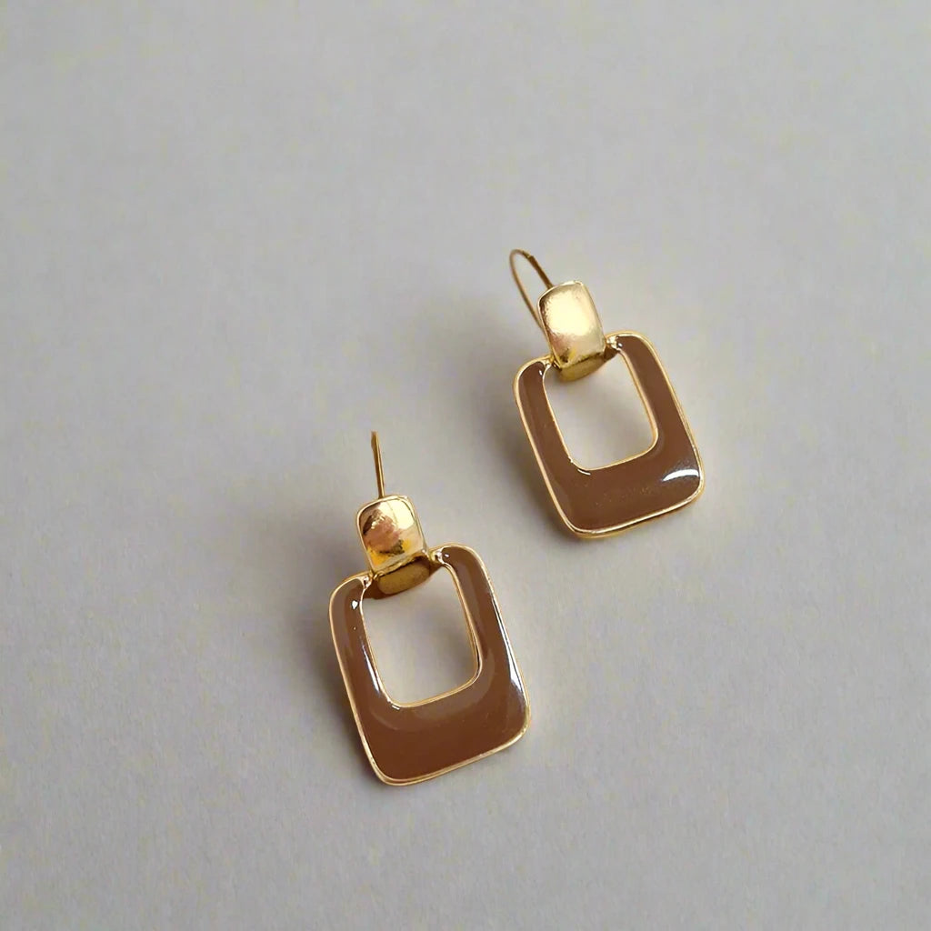 A pair of brown square drop earrings with a gold-tone frame.

