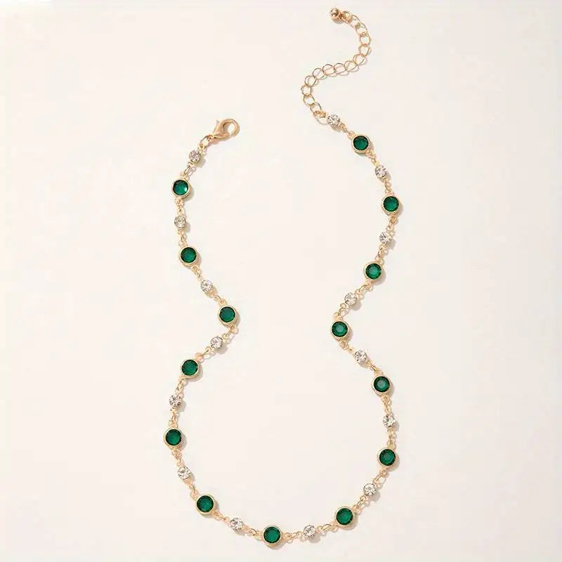 A minimalist gold choker with green and clear gemstones.