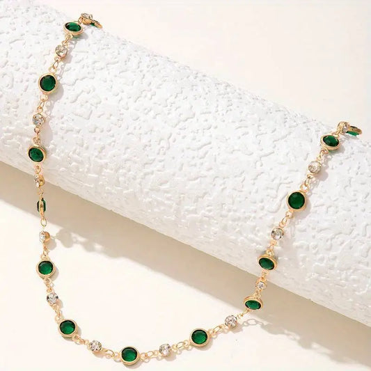 A gold chain choker with green and clear crystal beads.