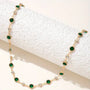 A gold chain choker with green and clear crystal beads.