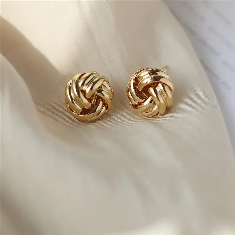 
A pair of gold knot stud earrings with a minimalist design.