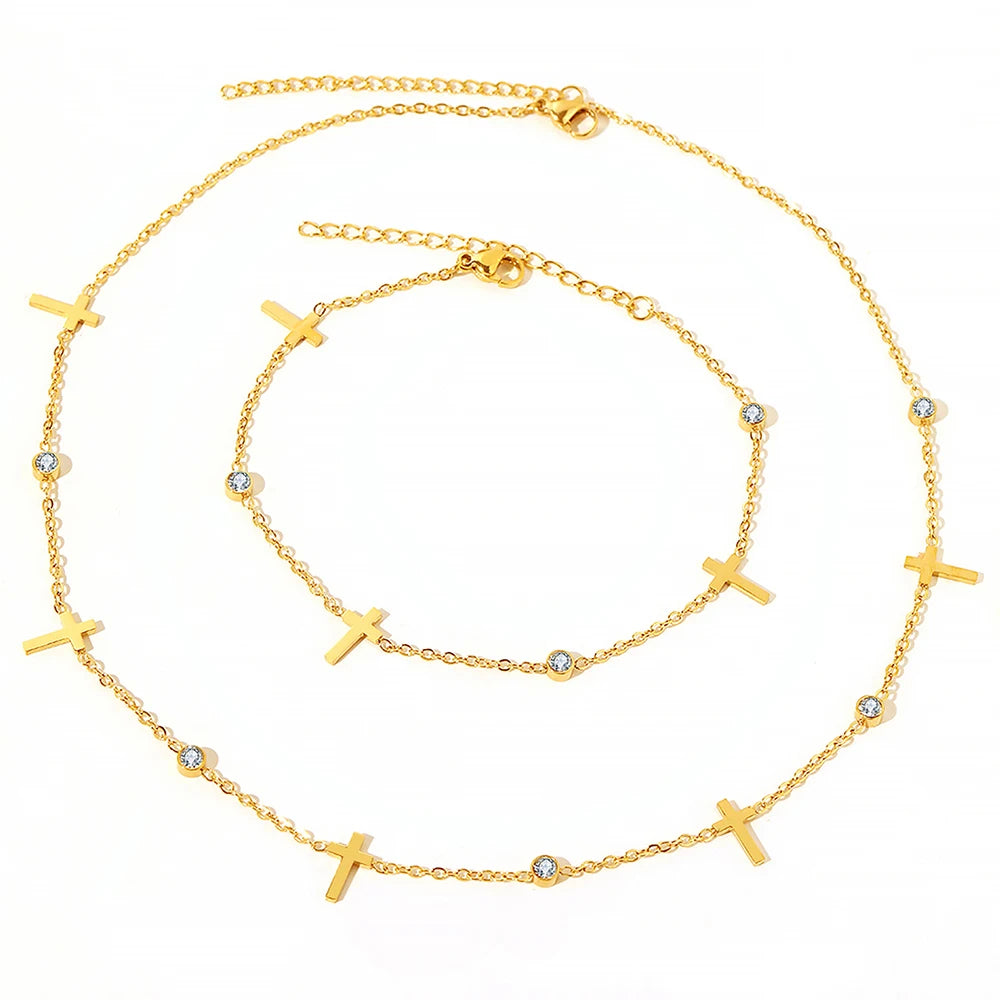 A set of two delicate gold necklaces with cross pendants and clear crystal accents.