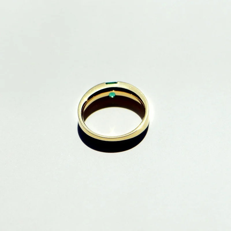 A minimalist gold band with a single square emerald.