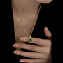 A gold chain necklace with a square emerald pendant set in a gold frame.