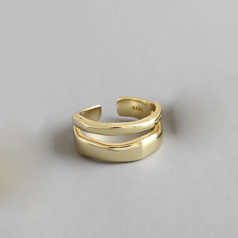 A set of two minimalist rings, one gold and one silver, with a simple layered design.