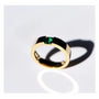 A modern gold ring with a square emerald gemstone.