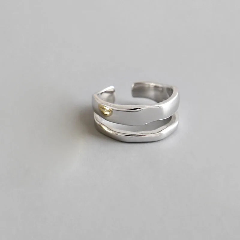 A set of two layered rings, one gold and one silver, with a minimalist design.