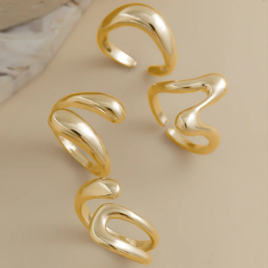 A set of four gold rings with organic, wavy shapes.