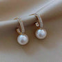 A pair of gold hoop earrings with a pearl drop and crystal accents.