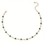 A simple gold choker with green and clear crystal accents.