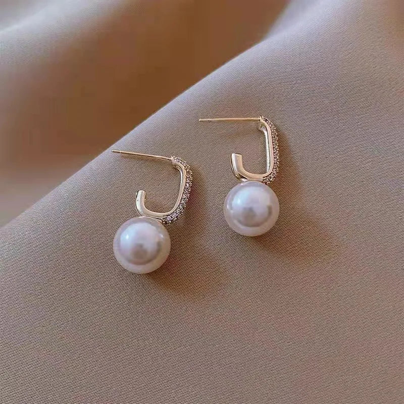 A pair of sparkly pearl drop earrings with crystal accents.