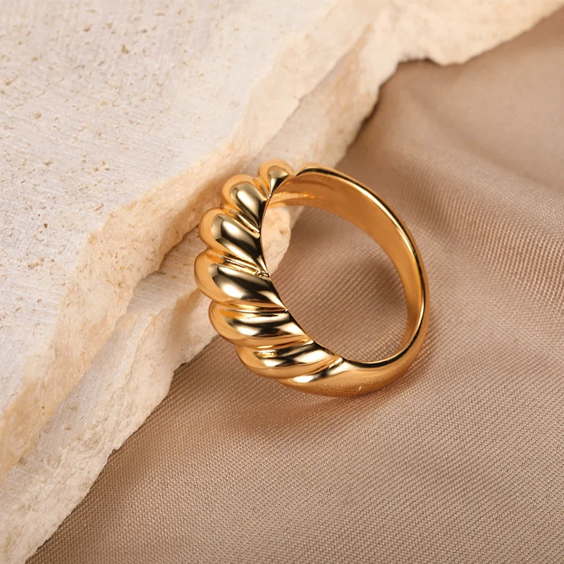 A gold ring with a bold, wavy design.