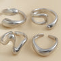 A set of four minimalist gold rings with wavy designs.